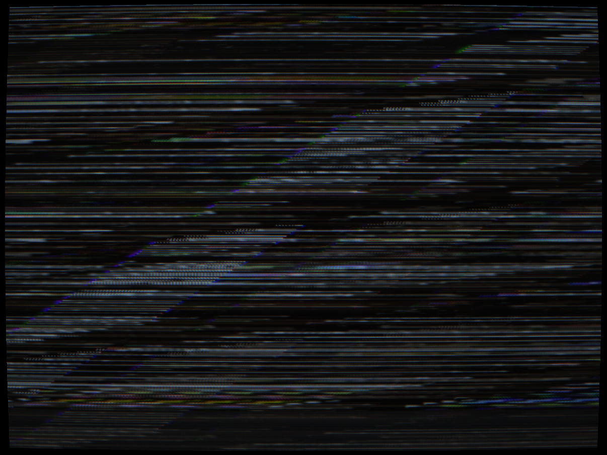 VideoCipher II (HBO/ESPN C-band satellite, 1986-1994) — NTSC composite with sync suppression plus per-line LFSR polarity inversion. Approximately 50% of lines have their luma complemented: white becomes black, the test card's white background inverts to near-black. Lines that are not inverted remain at nominal brightness. The combined effect of sync loss and line inversion makes the content completely unrecognisable — visible here as thin coloured scan lines against a predominantly black field.