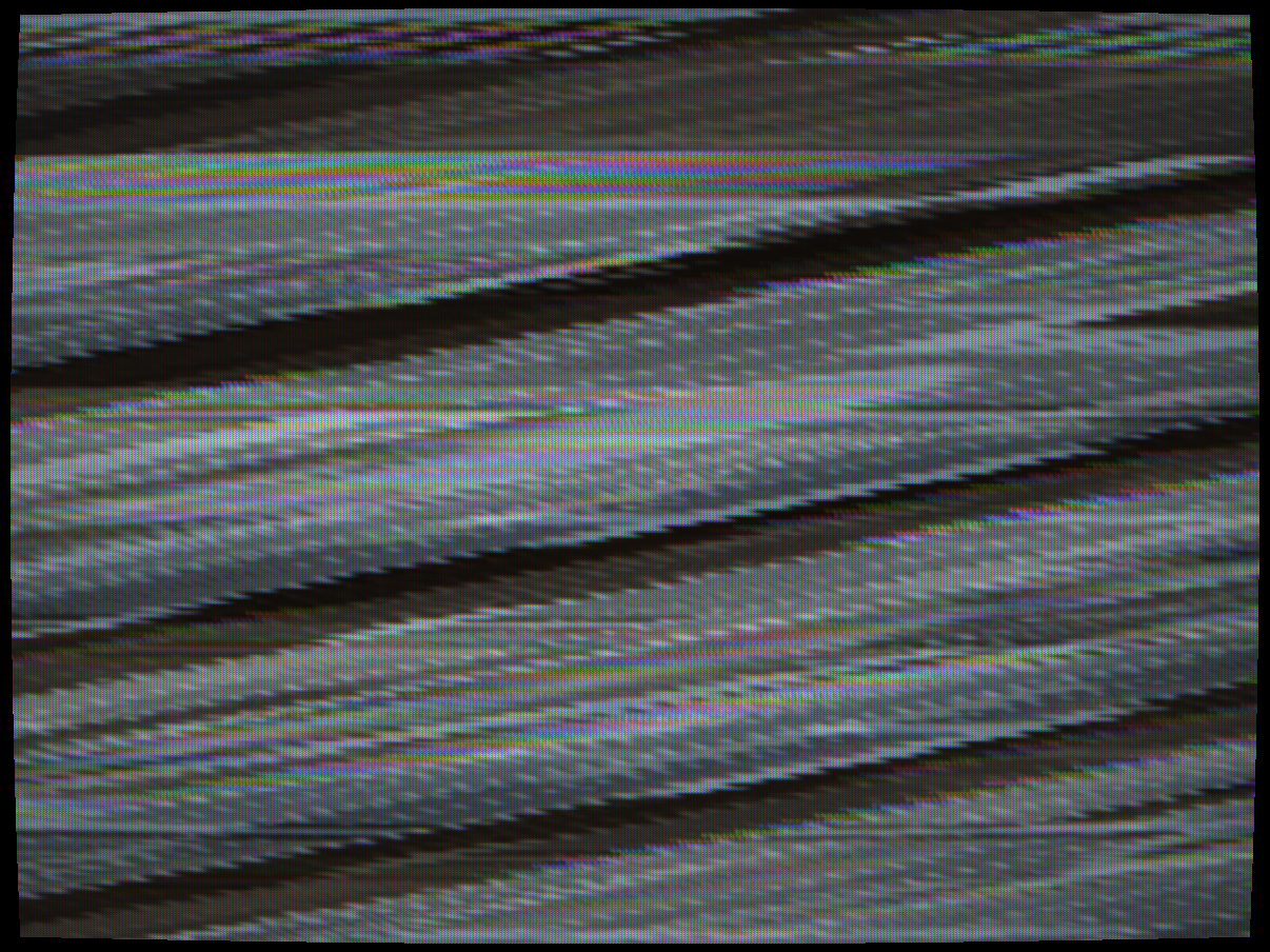Sync suppression (Oak Orion/Jerrold) — NTSC composite signal with sync tips raised to blanking level and colour burst randomised per line. The V-oscillator free-runs with no sync reference, causing continuous vertical roll. The H-oscillator loses lock and the picture tears horizontally. Each line's burst is replaced with a random-phase carrier, so the colour PLL cycles through hues on every line. The CRT scanline structure is visible in the noise — individual lines are sharp but completely displaced.